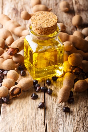 Oil from the seeds of Tamarindus indica in a glass jar close-up on a wooden table. verticalの写真素材