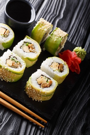 Japanese rolls green dragon with avocado, omelette tamago, sesame and cucumber closeup on a plate on the table. verticalの写真素材