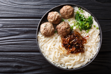 Traditional Indonesian beef meatball with noodles, fried onions, greens and broth close-up on a plate on the table. horizontal top view from aboveの写真素材
