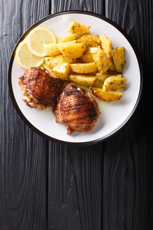 Greek food chicken thighs grilled with fried lemon garlic oregano potatoes closeup on a plate. Vertical top view from aboveの写真素材