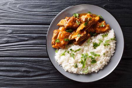 Stewed ribs in a spicy sauce served with white rice close-up on a plate. Horizontal top view from aboveの写真素材