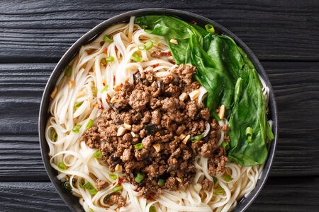 Traditional Chinese Sichuan Dan Dan Noodles with minced meat and greens in a plate on the table. Horizontal top view from aboveの写真素材