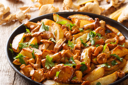 Freshly cooked potato wedges with wild chanterelle mushrooms close-up on a plate on the table....