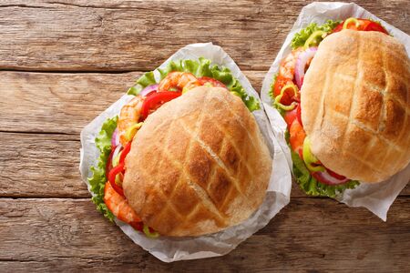 Pita with shrimps, tomatoes, peppers, onions and fresh lettuce close-up on parchment on the table. horizontal top view from aboveの写真素材