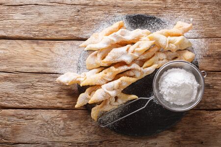 Traditional dessert Angel Wings Dusted with powdered sugar close-up on the table. horizontal top view from aboveの写真素材