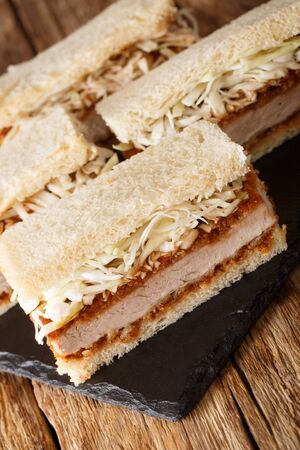 Homemade tender katsu sando sandwiches with tonkatsu sauce and cabbage close-up on a slate board on the table. verticalの写真素材