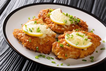 Crispy romano chicken breast fried breaded served with lemon and green onion close-up on a plate on the table. horizontalの写真素材