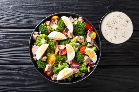 Healthy diet food salad with tuna, broccoli, tomatoes, onions and eggs close-up in a plate on the table.の写真素材