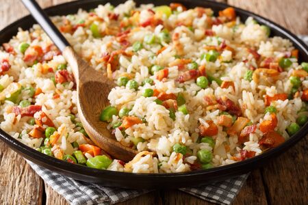 Tasty rice cooked with vegetables and bacon close-up in a plate on the table.の写真素材