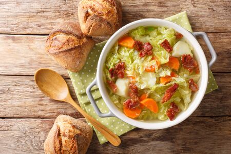Homemade savoy cabbage soup with fried bacon served with bread close-up in a bowl on the table. Horizontal top view from above
の写真素材