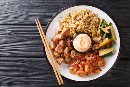 Serving hibachi of rice, shrimp, steak and vegetables served with sauce closeup in a plate on the table. Horizontal top view from above
の写真素材