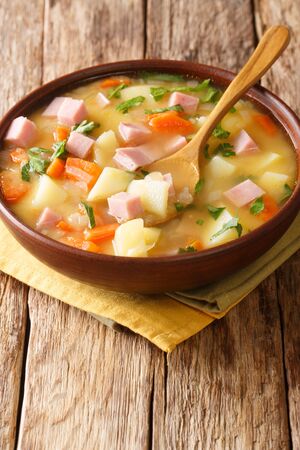 Spicy hot pea soup with potatoes, onions, carrots and ham close-up in a bowl on the table. vertical
の写真素材