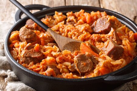 Traditional cabbage stew with meat, tomatoes, carrots and onions close-up in a pan on the table.の写真素材