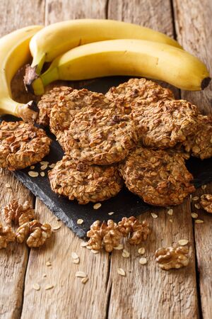 Tasty banana cookies with oatmeal and walnuts close-up on a slate board on the table. vertical
の写真素材