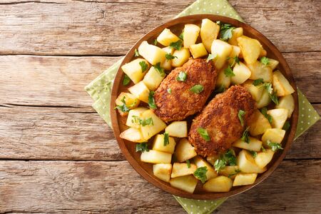 Traditional Russian cuisine pozharsky cutlets in breading with fried potatoes close-up in a plate on the table. Horizontal top view from aboveの写真素材