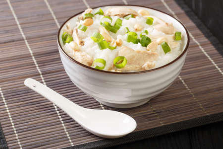 Slow cooked ginger rice porridge with chicken, peanuts and green onions close-up in a bowl on the table. horizontalの写真素材