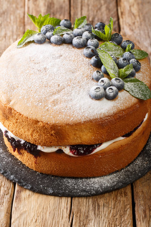 Sponge cake sandwich with blueberries and tender cream close-up on a slate board on the table....