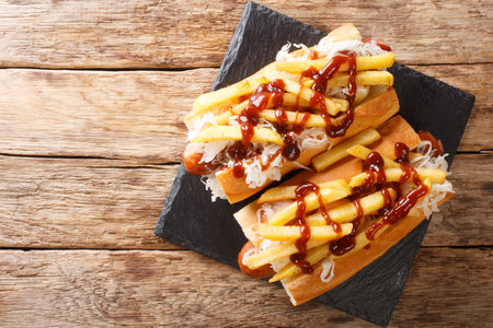 Polish boy's sandwich with sausage, cabbage salad, fries and barbecue sauce close-up on the table....