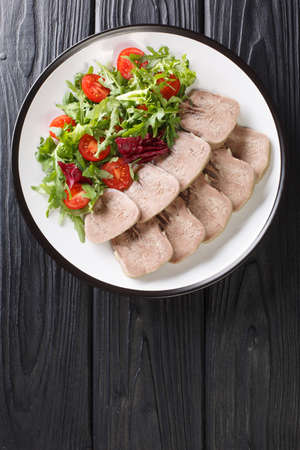 Boiled chopped beef tongue with fresh salad close-up in a plate on the table. vertical top view from aboveの写真素材