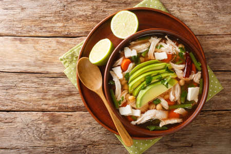 Caldo tlalpeno is a Mexican chicken soup with chickpeas and veggies close-up in a bowl on the table. horizontal top view from aboveの写真素材