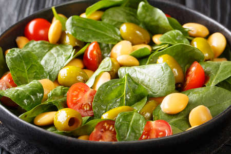 Mediterranean vegan salad of spinach, lupine beans, tomatoes and olives close-up in a plate on the table. horizontalの写真素材