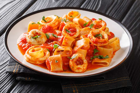 Authentic Italian Calamarata pasta with squid and tomato close-up in a plate on the table. horizontalの写真素材