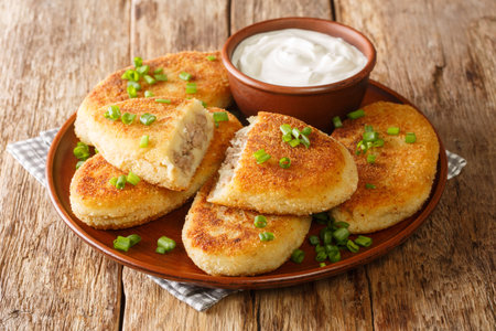 Ukrainian food potato zrazy with meat with sour cream close-up in a plate on the table. horizontal