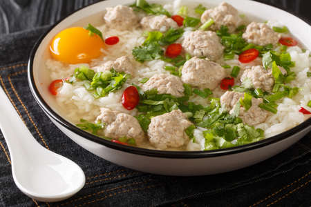 Asian food Thai Rice Soup with Pork meatballs Khao Tom Moo closeup in the plate on the table. Horizontalの写真素材