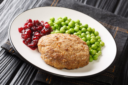 Swedish Luxurious Wallenbergare veal patties with green peas closeup in the plate on the table....