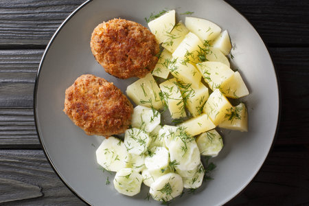 Polish pork meatballs Kotlety mielone with a side dish of boiled potatoes and cucumber salad close-up in a plate on the table. horizontal top view from aboveの写真素材