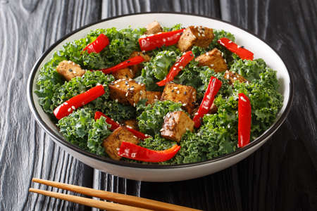 Serving of teriyaki tofu salad with bell peppers, kale and sesame seeds close-up in a bowl on the table. horizontalの写真素材