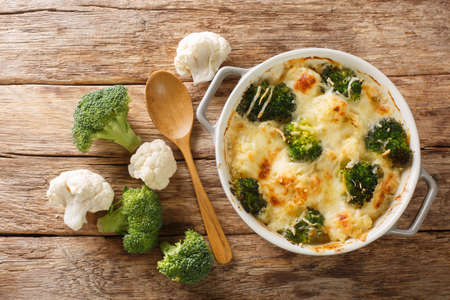 Cheesy creamy Broccoli Cauliflower Casserole close up in the dish on the old table. Horizontal top view from aboveの写真素材