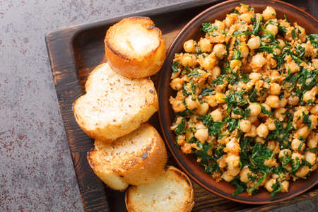 Spanish spinach and chickpeas served with toasts closeup in the plate on the table. Horizontal top view from aboveの写真素材