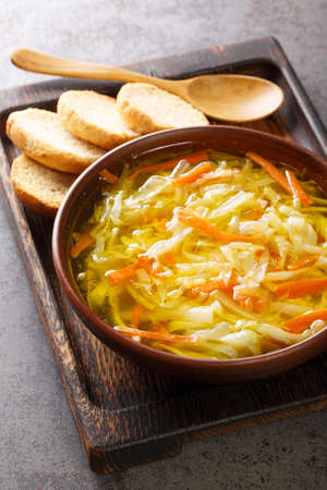 Sopa Juliana is a hearty Portuguese vegetable soup made with a combination of cabbage, carrots, turnips, onions, potatoes and spices closeup in the plate on the table. Verticalの写真素材