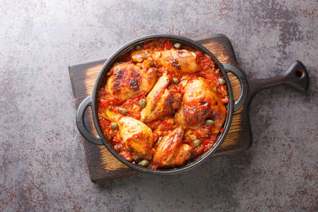 Spanish food chicken baked with tomato, pepper, onion and garlic sauce close-up in a frying pan on a cutting board. horizontal top view from aboveの写真素材