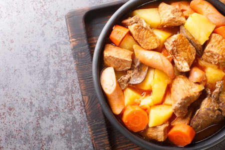 Filipino pork menudo traditionally consists of chunks of pork that is stewed in a tomato sauce close up in the plate on the table. Horizontal top view from aboveの写真素材