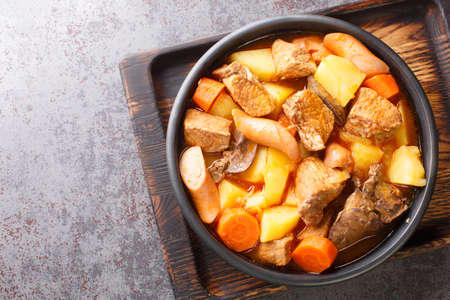 Tasty Pork Menudo is a Filipino stew dish that is typically made with pork, liver, tomatoes, potatoes, and other vegetables close up in the plate on the table. Horizontal top view from aboveの写真素材