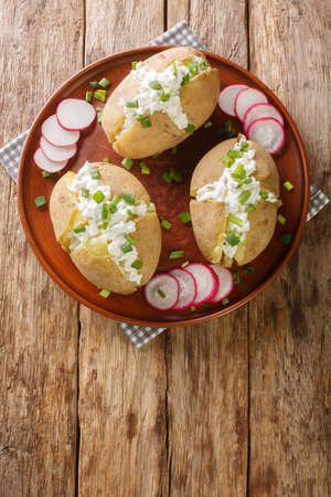 Pyry z gzikiem is a dish of Poland cuisine which consists of potatoes in jacket, salty curd cheese and green onion closeup on the plate on the table. Vertical top view from aboveの写真素材