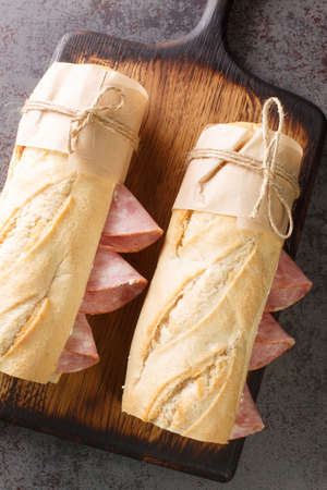 French sandwich crusty baguette, lightly salted butter and thinly sliced ham, ideally Jambon de Paris closeup on the wooden board. Vertical top view from aboveの写真素材
