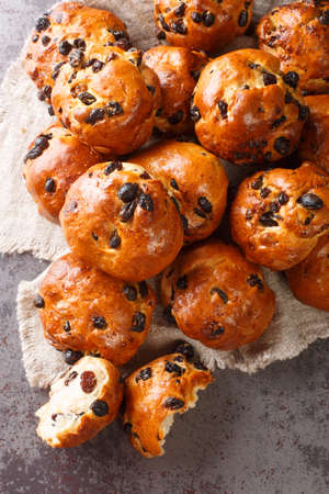Currant bun is a European sweet bun that contains currants or raisins closeup on a table. Vertical top view from aboveの写真素材