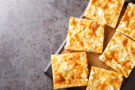 Greek traditional cheese pie with feta close-up on a wooden board on the table. horizontal top view...