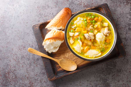 Homemade chicken soup with carrots, onions, celery root and parsley and semolina dumplings close-up in a bowl on the table. horizontal top view from aboveの写真素材