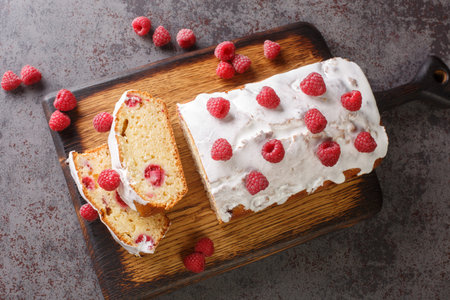 Sliced Raspberry loaf cake bread with white glaze close-up on a wooden board on the table....