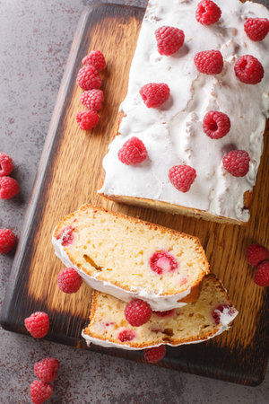 Delicious fresh raspberry bread cake with white icing close-up on a wooden board on the table....