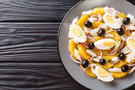 Remojon salad of oranges, boiled salted fish, eggs and red onions close-up in a plate on the table. Horizontal top view from aboveの写真素材