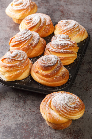 Cruffins flaky and buttery and covered with powdered sugar closeup in the muffin pan on the table. Verticalの写真素材