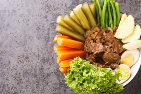 Selat Solo Javanese dish of braised beef steak in sweet soy sauce with eggs, potatoes and vegetables closeup in the bowl on the table. Horizontal top view from aboveの写真素材