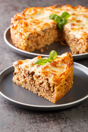 Spaghetti pie with Ground beef, cheese, tomato sauce closeup in the plate on the table. Verticalの写真素材