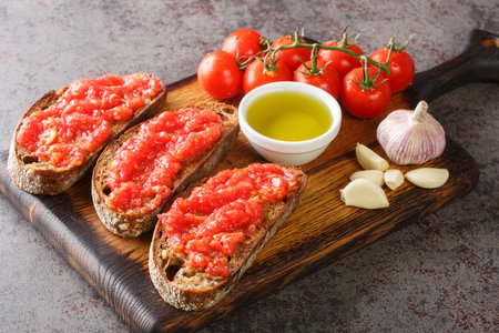 Catalonian cuisine Pan Con tomate, bread with tomato and garlic closeup on the wooden board on the table. Horizontalの写真素材