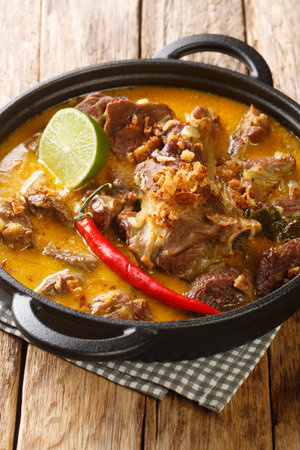 Lamb Curry or Indonesian Gulai Kambing for Eid closeup on the pan on the wooden table. Vertical
